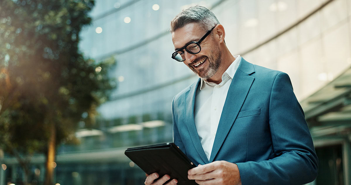 Mann mit Tablet in der Hand vor einem modernen Gebäude